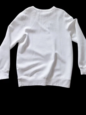 Vit sweatshirt från Polo Ralph Lauren - Klassisk vit sweatshirt från Polo Ralph Lauren med rund halsringning och den ikoniska lilla loggan broderad på bröstet. Tröjan har ribbade muddar vid ärmslut och nederkant. Tillverkad i mjukt bomullsmaterial som är skönt mot huden.