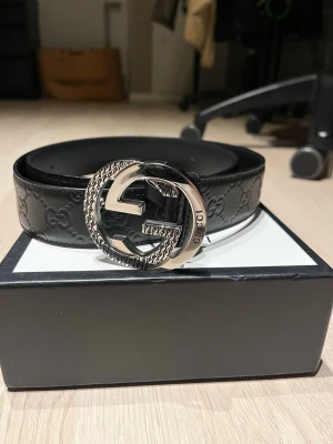 Gucci Bälte - Snyggt svart skärp från Gucci i skinn med präglade GG-loggor längs hela bandet. Bältet har ett stort, rundat silverfärgat GG-spänne med detaljerad kant och Gucci-gravyr. Kan gå ner i pris via snabb deal! 