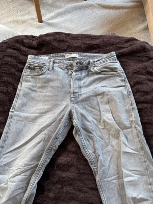 Grå raka jeans från jack & jones - Säljer ett par grå jeans från jack & jones med rak passform och klassisk femficksdesign. Jeansen har bälteshällor, knappgylf och är tillverkade i ett mjukt denimtyg. Perfekta för en avslappnad och trendig look.