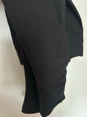 Svarta ekologiska leggings - Säljer ett par svarta leggings i mjukt och stretchigt material, certifierade enligt GOTS för ekologisk bomull. De har en bred resår i midjan och sitter tight längs benen. Perfekta för en chill och enkel look.