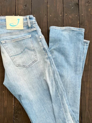 Ljusblå jeans från Jacob Cohën - Snygga ljusblå jeans från Jacob Cohën   Jeansen har en ljus tvätt och är riktigt stilrena. Tillverkade i mjukt och stretchigt material och har detaljer i blått på fickan och bakre etiketten.