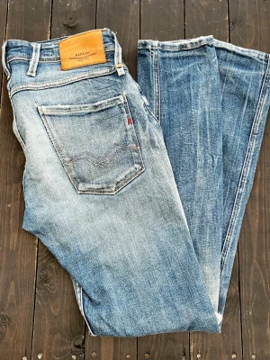 Blå slitna jeans från Replay - Säljer ett par blå Replay Anbass Jeans med slitningar och fade. Jeansen , ljus tvätt och detaljerade slitningar. Jeansen har en riktigt najs fade och passar till allt. Hör av er vid frågor!🙌