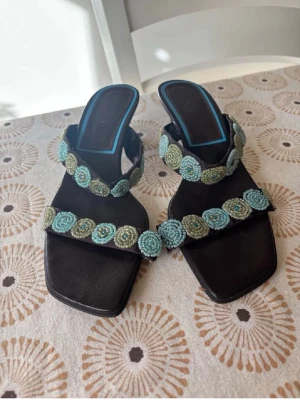 Svarta sandaler med pärlbroderi - Tappat några pärlor på ett ställe, annars fina. Klacken är ca 3cm
