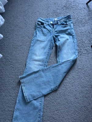 Ljusblå bootcut jeans - Säljer ett par ljusblå bootcut jeans med klassisk femficksdesign och låg midja. Jeansen har en lätt tvättad look och är bootcut. De kommer från gina tricot och är i storlek 158. Säljer pga för små för mig, jätte fina och har inga defekter. 