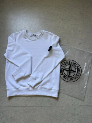Vit sweatshirt från Stone Island - Säljer en helt ny Stone Island-tröja i storlek S. Tröjan är aldrig använd och är i nyskick. Bekväm passform, mjukt material och den klassiska Stone Island-badgen på ärmen. Passar perfekt till både vardag och en mer stilren outfit.  Information:  * Märke: Stone Island * Storlek: S * Skick: Helt ny och oanvänd * Bekväm passform * Hög kvalitet  Skickas eller hämtas enligt överenskommelse. Hör gärna av dig vid frågor eller intresse!