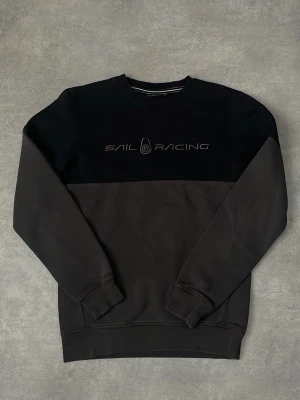 Svart sweatshirt  - Snygg svart sweatshirt från SR med diskret logga på bröstet. Tröjan har rund hals, långa ärmar och ribbade muddar vid ärmslut och nederkant. Perfekt till en avslappnad stil och enkel att matcha med jeans eller joggers.