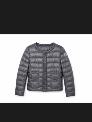 Svart dunväst med fickor - Snygg svart dunväst med quiltad design och två stora framfickor. Västen har rund halsringning, dragkedja framtill och Moncler-logga på ärmen. Tillverkad i glansigt material som ger en modern look.