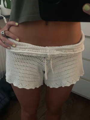 Vita stickade shorts med snörning - Säljer ett par vita stickade shorts med snörning i midjan och vågig kant nertill från GinaTricot. De har en luftig och mjuk känsla, perfekta för varma dagar. 