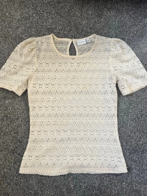 Beige spetsblus från Vila - Söt beige spetsblus från Vila med korta puffärmar. Använd några gånger. Säljer för att den inte kommer till användning💕 Nypris 349kr