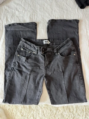 Mörkgrå raka jeans med fem fickor - Säljer ett par mörkgrå jeans med raka ben och klassisk femficksdesign. Jeansen har bälteshällor, knappgylf och sömmar i matchande färg. Perfekta för en avslappnad och stilren look. Materialet är denim med lätt stretch.
