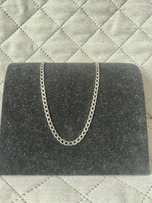 Silverfärgat kedjehalsband - Snyggt halsband i silverfärg med breda, platta länkar i klassisk kedjedesign. Halsbandet har en enkel och stilren look som passar till många olika outfits. Materialet är i rostfritt stål med blank finish. Perfekt för dig som gillar minimalistiska accessoarer. Finns 4 st just likadana just nu. 50cm.