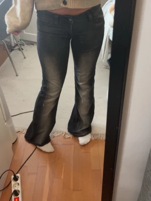 Weekday jeans  - Säljer ett par svarta bootcut jeans med snygga slitningar och tvättade detaljer längs benen. Jeansen har normal midja och klassisk femficksmodell. Perfekta för dig som gillar en retro och avslappnad stil.