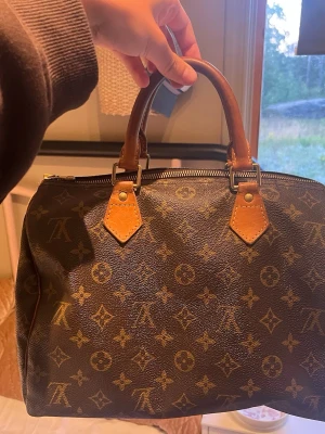 Louis Vuitton monogram handväska - Säljer en klassisk Louis Vuitton, Sppeddy 30. Handväska i brunt monogrammönster med ljusbruna läderhandtag. Väskan har guldfärgade metalldetaljer och dragkedja upptill. Perfekt storlek för det viktigaste. Ny pris på Speedy 30 är ca 20 tusen. 