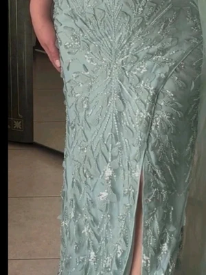 Ljusgrön balklänning med slits - Elegant ljusgrön långklänning med glittriga broderier och en hög slits framtill. Klänningen är axelbandslös och har en figurnära passform som framhäver midjan. Perfekt för speciella tillfällen när du vill sticka ut.