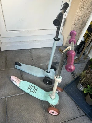 Två sparkcyklar för barn - Säljer två trehjuliga sparkcyklar för barn. Den ena är ljusblå med svarta handtag och hjul, den andra är mintgrön med rosa handtag och hjul. Båda har stabila plattformar i plast och metallram. Perfekt för lek utomhus och enkel att styra. 2 st för 300kr eller 1 för 200kr