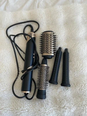 Rusta multistyler airwrap - En svart multistyler för hår med flera utbytbara borsthuvuden i metall och plast. Inkluderar två rundborstar med piggar och två smalare tillbehör. Perfekt för att styla och forma håret på olika sätt. Den är helt oanvänd, nypris 1000 kr men säljer för 300kr 💗