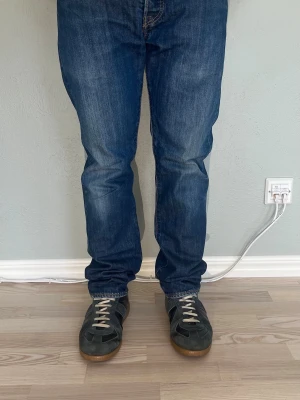 Levi's 501 W30 L32 – Mörkblå vintage wash | Straight fit | 100% bomull - LEVI’S 501 ORIGINAL  Storlek: W30 L32 Passform: Straight fit, hög midja Färg: Mörkblå med naturlig vintage wash Material: 100% bomull  Klassiska 501:or med den ikoniska läderpatchen — Levi Strauss & Co., San Francisco. Knappgylf och orangea nitar som det ska vara på en äkta 501. Mörkblå tvätt som funkar till det mesta, från vit t-shirt till kavaj.  Modellen på bilden är 175 cm och väger 65 kg.  Skick: Mycket bra skick utan defekter. Nypris: ca 1 299 SEK
