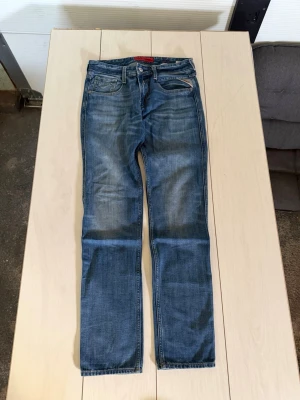 Blå jeans från Replay, rak modell - Snygga blå jeans från Replay i rak modell med klassisk femficksdesign REAR UT DOM!! ORG PRIS 499, NU ENDAST 299!. Jeansen har slitningar och tvättade detaljer för en avslappnad look. Tillverkade i bomull med en bekväm passform. Perfekta för dig som gillar en tidlös stil.