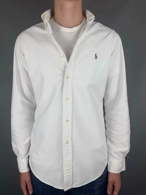 Ralph Lauren skjorta - Ralph Lauren Skjorta Märke: Polo Ralph Lauren Storlek: M Passform: Customfit Färg: Vit Skick: Mycket bra, möjligtvis superlite gulnad under armarna (syns knappt) se bildr. Beskrivning: utan defekter. Modellen på bilden: 183 cm / 74 kg