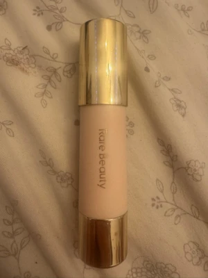 Rare Beauty bronzer stick - Krämig bronzer stick från Rare Beauty i en varm brun nyans. Förpackningen är ljusbeige med guldfärgade detaljer och har en smidig twist-up funktion. Perfekt för att skapa naturlig solkysst look och enkel att applicera direkt på huden. Den är använd men det finns mycket kvar 