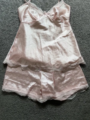 Ljusrosa satinpyjamas set med spets - Sött ljusrosa pyjamasset i satin med linne och shorts. 