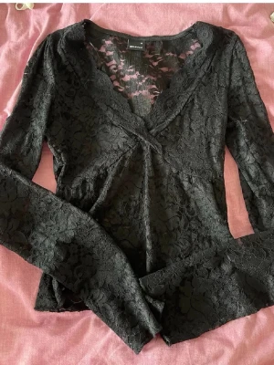 Svart spetsblus från Gina Tricot - Supersnygg svart spetsblus från Gina Tricot med v-ringning och långa ärmar. Storlek XS