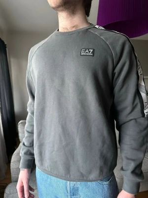 Armani sweatshirt - Grå sweatshirt från EA7 Emporio Armani med logga på bröstet och längs ärmarna. Tröjan har rund halsringning och är tillverkad i mjukt material. Storlek M💫