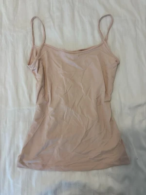 ljusrosa linne - Säljer en enkel och stilren beige linnetopp från H&M. Toppen har tunna axelband och ärmlös design, perfekt för varma dagar eller som lager under andra plagg. Tillverkad i mjuk bomull för skön känsla hela dagen.