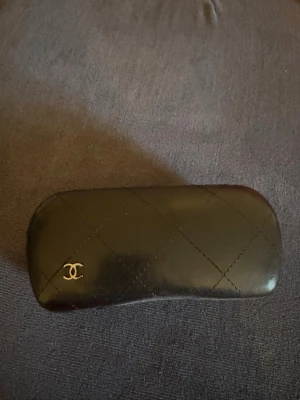 Chanel vita och svarta solglasögon - Säljer ett par trendiga solglasögon från Chanel med vit båge och svarta detaljer. Stora Chanel-loggor på sidorna och medföljande svart fodral i quiltad design. Perfekt accessoar för dig som vill sticka ut med en lyxig look.