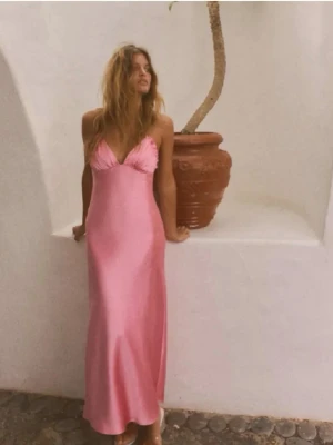 Rosa balklänning med öppen rygg - Snygg rosa långklänning i satin med smala axelband och öppen rygg med snörning. Klänningen har en v-ringad urringning och en figurnära passform som ger en elegant siluett. Perfekt för sommarens alla tillfällen eller bal!