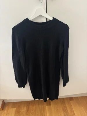 Svart stickad klänning från Object - En svart stickad klänning från Object i storlek XS. Klänningen har lång ärm, rund halsringning och en enkel, rak passform. Perfekt för dig som gillar en stilren och mysig look.