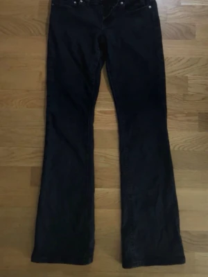 Svarta bootcut jeans från Gina Tricot - Säljer ett par svarta bootcut jeans från Gina Tricot. Jeansen har klassisk femficksdesign, silverfärgade knappar på bakfickorna och är tillverkade i denim. Perfekt för dig som gillar en retrostil med utsvängda ben.