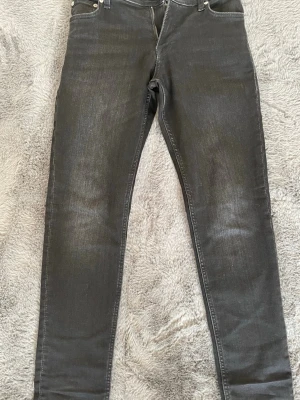 Svarta slim fit jeans - Snygga svarta slim fit jeans med klassisk femficksdesign och dragkedjegylf. Jeansen har en lätt tvättad look och smal passform som sitter tajt längs benen. Perfekta för en stilren och modern outfit.