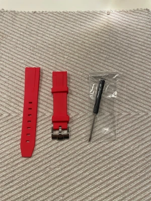 OMEGA MOONSWATCH - Rött klockarmband i silikon - Snyggt rött klockarmband i silikon med metallspänne. Perfekt för dig som vill byta stil på din klocka. Medföljer gör ett verktyg för enkel montering. Passar de flesta sport- och smartklockor med standardfäste. 