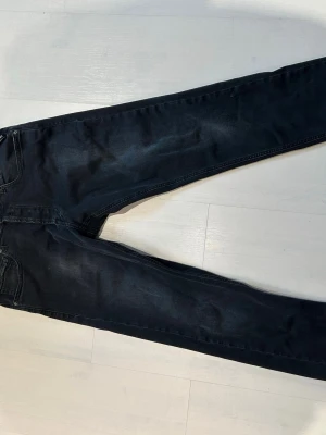 Replay Grover Jeans Svarta/Gråa W32 L32 - Snygga mörka slim fit jeans med klassisk femficksdesign och lätt tvättade detaljer. Jeansen har smal passform och är tillverkade i ett stretchigt denimtyg för extra komfort. Storlek W32 L32 och är slim fit. Köpta nya i butik( har kanske kvitto kvar men är osäker) Väldigt bra skick. Hör av er vid frågor. MVH Viggo