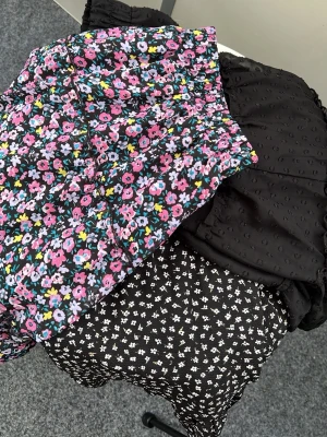 Tre kjolar med olika mönster - Säljer tre snygga kjolar: en svart med små vita blommor, en svart med struktur och en färgglad blommig kjol i rosa, blått och vitt. Perfekta för dig som gillar att mixa mönster och färger. Alla är korta och har en trendig look. Mystery bag med tre olika kjolar i storlek L fast inte direkt L mer som M.
