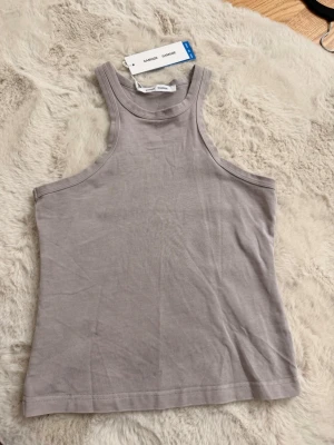 Grå linnetopp från Samsøe Samsøe - Säljer en stilren grå linnetopp från Samsøe Samsøe, modell Helene Tank Top. Toppen är ärmlös med rund halsringning och har en enkel, rak passform. Helt ny med prislapp 🌸