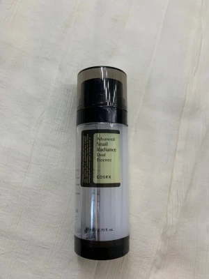 COSRX Advanced Snail Radiance Essence - COSRX Advanced Snail Radiance Dual Essence är en toner i en genomskinlig plastflaska med svart pump och lock. Produkten har en ljusgul etikett och innehåller snigelsekret för extra lyster och återfuktning. Perfekt för dig som vill ha glow och mjuk hud.