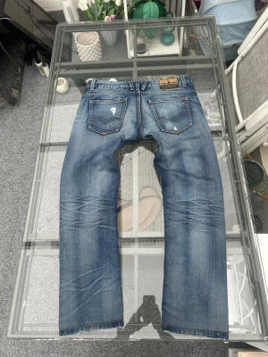 Replay jeans W34/L33 – vintage wash - Säljer ett par Replay Blue Jeans i storlek W34/L33. Ljusblå vintage wash med snygga fades och slitna detaljer som ger riktigt clean Y2K/streetwear-look.  Bra passform och sköna till både vardag och sommaren. Passar perfekt till oversized tees, hoodies och sneakers.  • Storlek: W34/L33 • Ljusblå denim • Vintage wash • Replay Blue Jeans • Bra skick