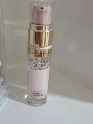 Max Factor Miracle Glow Highlighter - Max Factor Miracle Glow Pro Illuminator är en flytande highlighter i en elegant pumpflaska med guldiga detaljer. Färgen är ljus och skimrande, perfekt för att ge ansiktet en fräsch glow. Produkten är enkel att applicera och passar till alla hudtoner.