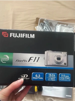 Fujifilm FinePix F11 digitalkamera - Säljer en silverfärgad Fujifilm FinePix F11 digitalkamera med 6.3 megapixlar, 18.5x zoom (3x optisk, 6.2x digital) och en stor 2.5-tums LCD-skärm. Kameran har ett kompakt format och är tillverkad i metall och plast.