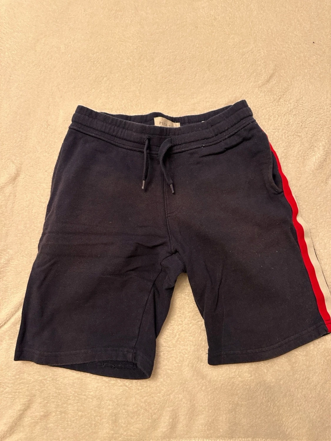 Mörkblå shorts med rödvit sidoremsa