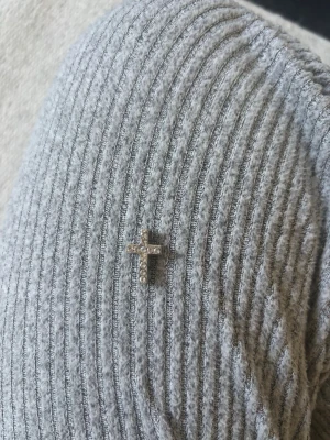 Silverfärgad korsberlock med stenar - Snygg liten korsberlock i silverfärg med gnistrande stenar på framsidan. Perfekt att fästa på ett armband, halsband eller som charm på en väska. Enkel och stilren design som passar till många olika stilar🌸