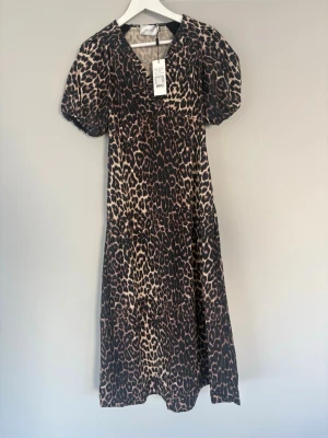 Leopardmönstrad långklänning Neo Noir - Säljer en snygg långklänning från Neo Noir med leopardmönster. Klänningen har v-ringning, puffärmar och en figurnära passform. Perfekt för dig som vill sticka ut med ett djurmönster. Materialet är mjukt och följsamt. Oandvänd och prislapp sitter kvar!