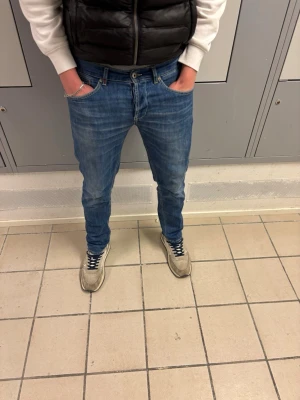 Dondup jeans med slitningar - Snygga blå slim fit jeans med lätt slitna detaljer och klassisk femficksmodell. Jeansen har normal midja och smal passform som sitter tajt över benen. Perfekta för en avslappnad och trendig look. Materialet är troligtvis bomull med stretch för extra komfort. Märket är dondup, jeansen är såklart äkta. Dondups upplevs ofta små i storleken.