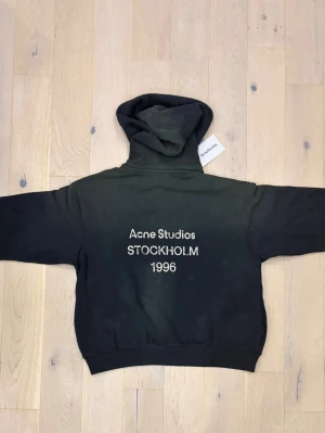 Svart hoodie från Acne Studios - Svart hoodie från Acne Studios med tryck på ryggen där det står 'Acne Studios STOCKHOLM 1996'. Jobbar på Acne Studios i Stockholm och fick denna som avskedsgåva, tyvärr vart den för stor😅🫶Nypris: 5300 Kr