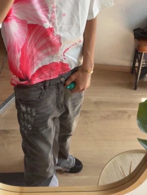 Gråa baggy jeans med tryck - Säljer ett par gråa baggy jeans med coolt tryck på vänster ficka. Jeansen har en avslappnad passform och klassisk femficksdesign. Perfekta för en streetwear-look och passar till det mesta i garderoben. Använd 5 gånger , fick i present 