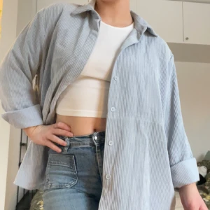 Ljusblå manchesterskjorta - Säljer en oversized ljusblå manchesterskjorta. Skjortan har klassisk krage, knappar framtill och långa ärmar som kan vikas upp. Tillverkad i mjuk bomull och passar perfekt till jeans eller kjol. Säljer eftersom den inte kommer till användning längre. Passar även bra som tunn jacka på sommaren