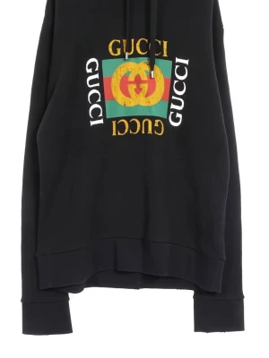 Svart hoodie från Gucci med logga - Svart hoodie från Gucci med stor färgglad logga och text på bröstet. Klassisk huva med dragsko och ribbade muddar. Trycket har gröna, röda och gula detaljer samt dubbla G-symbolen. Perfekt för dig som gillar streetwear och exklusiva märken.