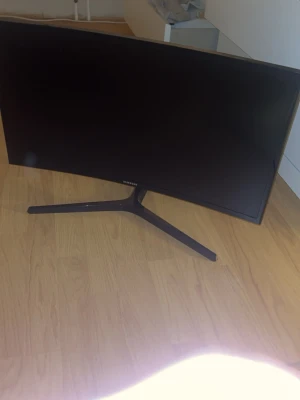 Curved 60 hz samsung gaming skärm - Säljer en bred, svart datorskärm från Samsung med modern, böjd design och smal ram. Skärmen står på ett stabilt stativ i metall och passar perfekt för gaming eller arbete där extra skärmyta behövs.